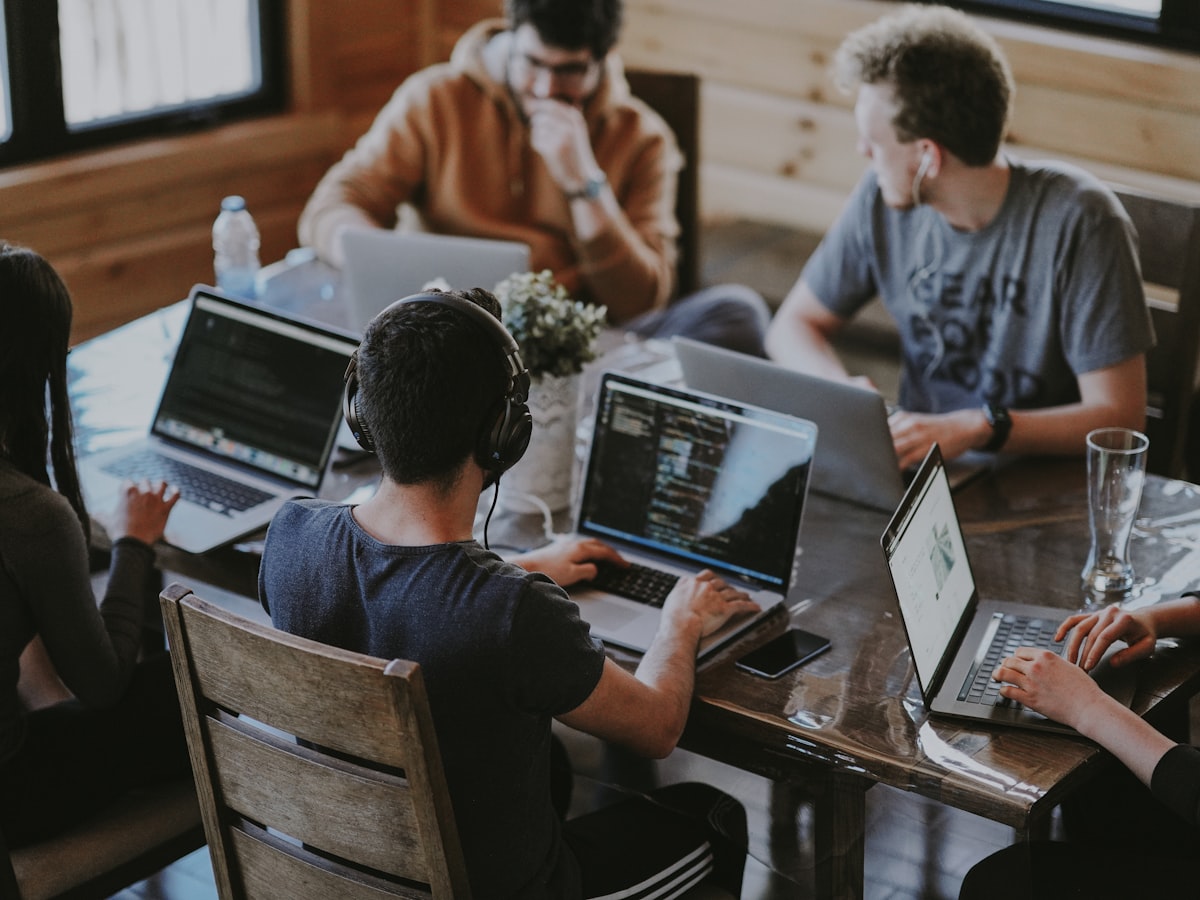 Equipo trabajando de forma colaborativa en notebooks alrededor de una mesa